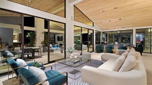 A spacious living area with a large glass wall, a modern kitchen, and a seating area with a sofa and armchairs.