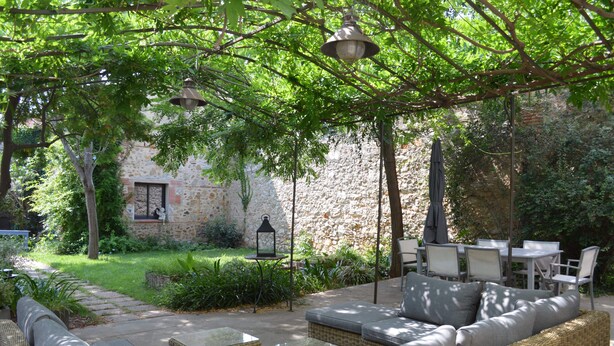 A patio with outdoor furniture, a stone wall, and greenery. - La Maison d'Antoine (Rivesaltes)