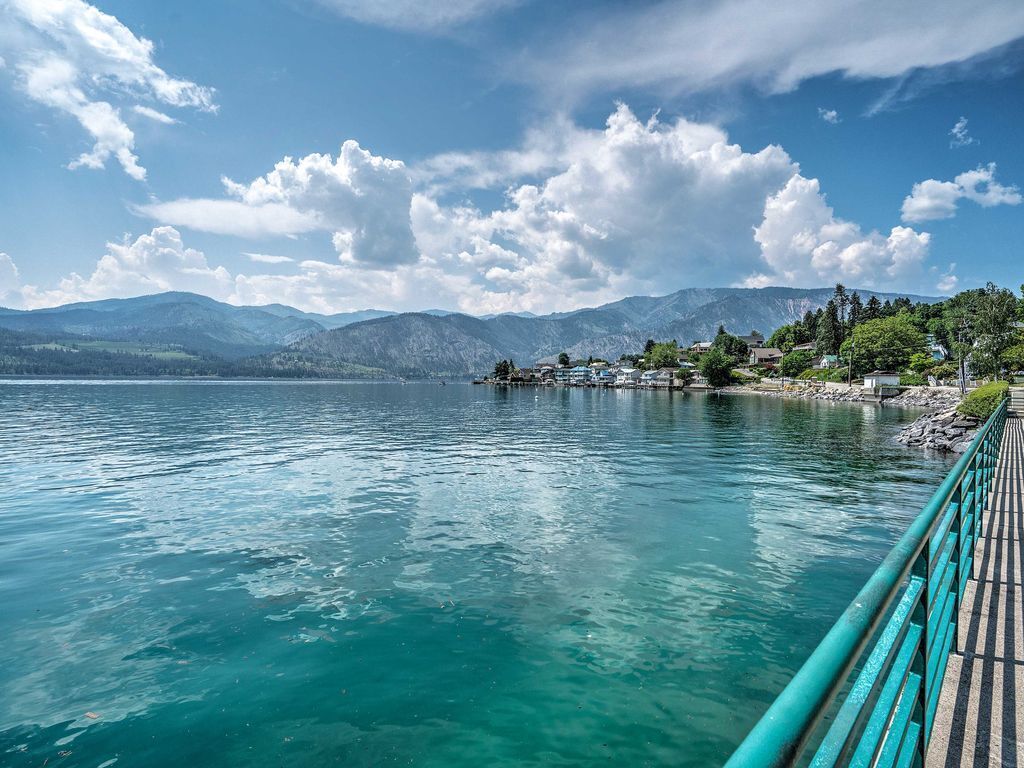 Un lac bordé d’un ciel bleu azur et dominé par des montagnes à l’horizon.