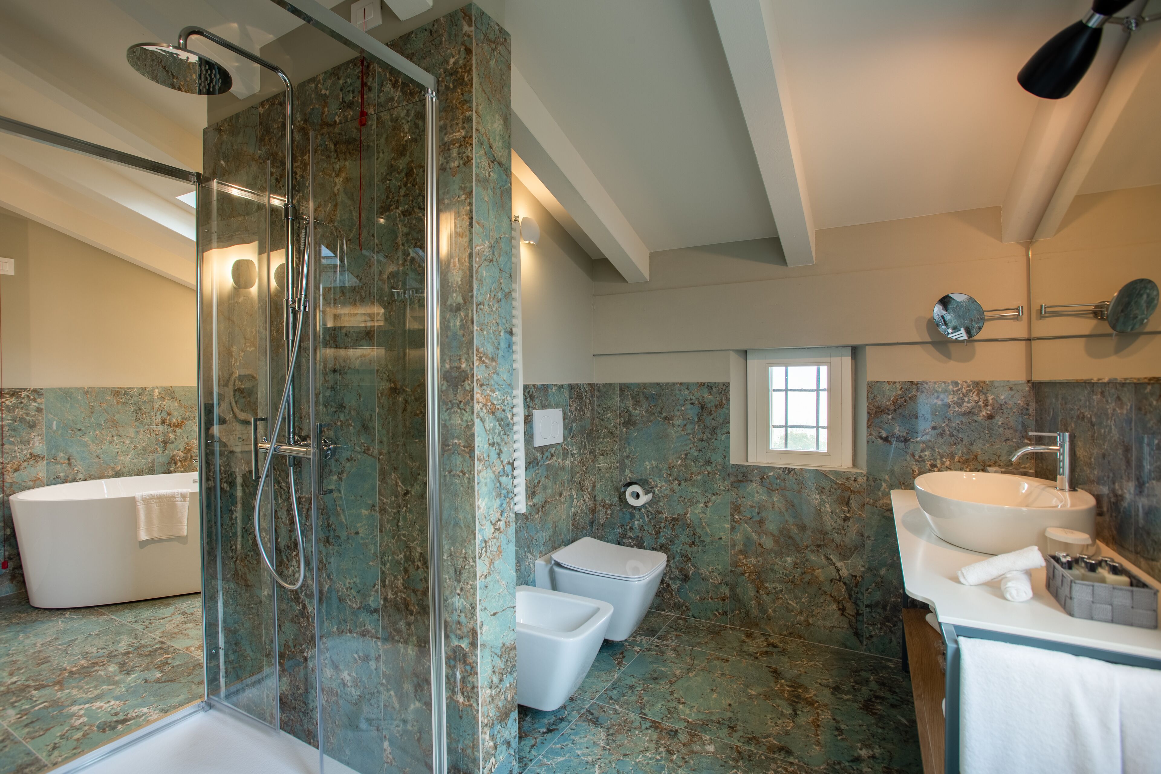 Une salle de bain moderne dotée d’une douche à parois de verre, d’une baignoire sur pieds, de toilettes et d’un lavabo avec un plan de travail en marbre.