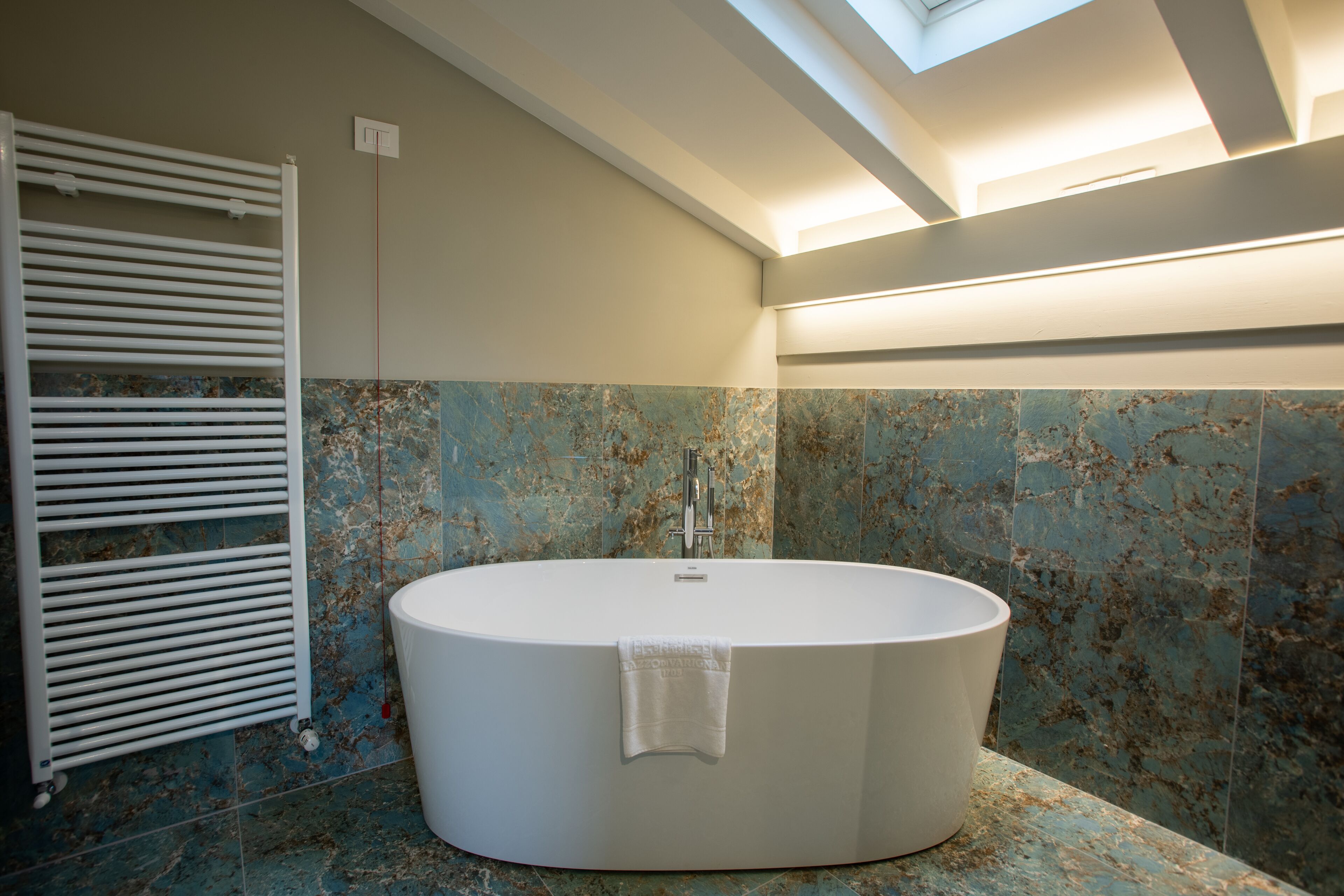 A modern bathroom with a freestanding bathtub, a towel rack, and a skylight.