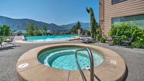 Ein Poolbereich mit Whirlpool, Liegestühlen und Blick auf die Berge.