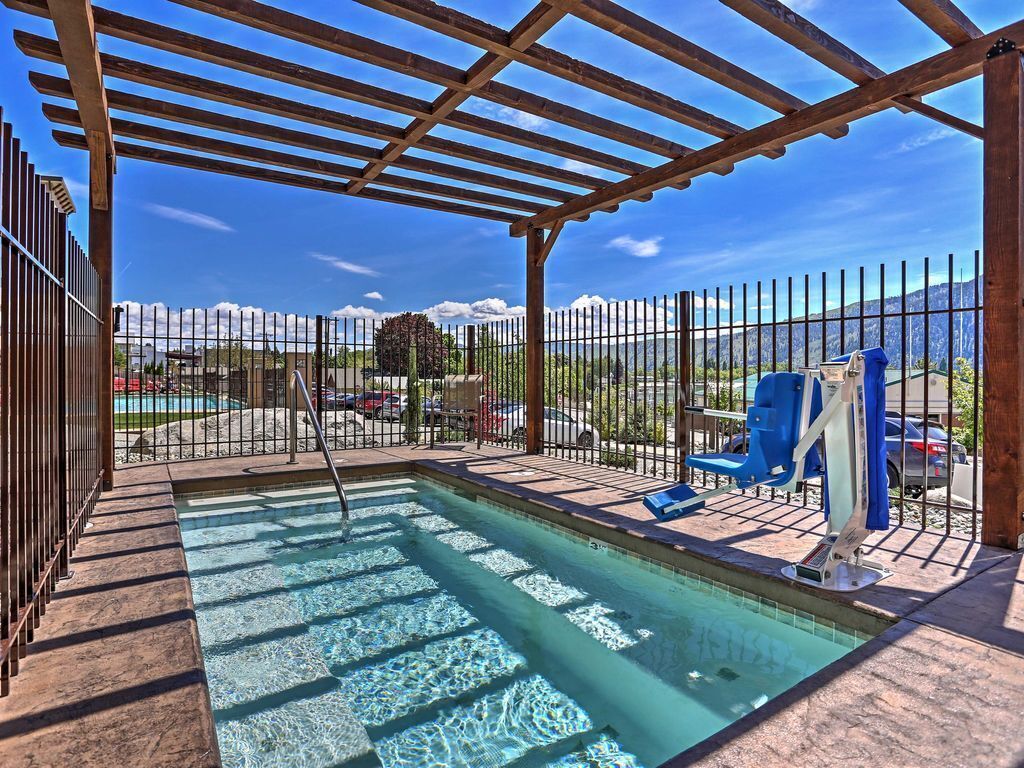 A pool area with a pergola, a fenced pool, and a view of mountains.