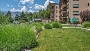 A multi-story building with balconies, a well-maintained lawn, and a mountainous backdrop. - Majestic Views / Lake Chelan / Pool and Spas! (Manson)