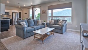 A modern living room with two grey sofas, a wooden coffee table, and a kitchen in the background. - Epic Views of Lake Chelan, Modern Condo, Pool, Spa (Manson)