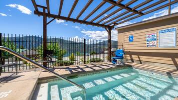A pool area with a wooden pergola, a fence, and a signboard with spa rules.