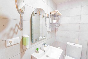 A modern bathroom with a white sink, a mirror, a towel rack, and a toilet.