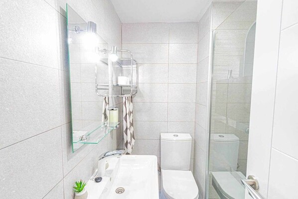 A modern bathroom with a glass shower enclosure, a white sink, and a toilet.