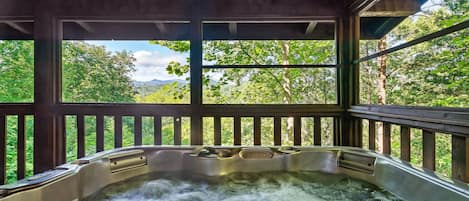 Un jacuzzi con vistas a un bosque y montañas.