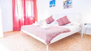 Ein Schlafzimmer mit Bett, Kissen, einem Nachttisch und einem Fenster mit Vorhängen.