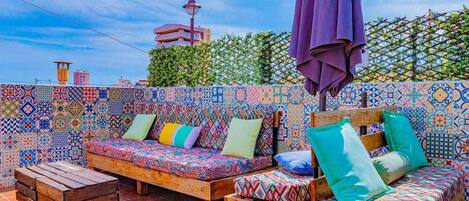 Una terrazza sul tetto con pareti piastrellate dai colori vivaci, una panca di legno e un divano decorato con cuscini.