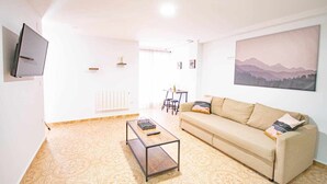Ein Wohnzimmer mit einer Couch, einem Couchtisch und einem an der Wand montierten Fernseher.