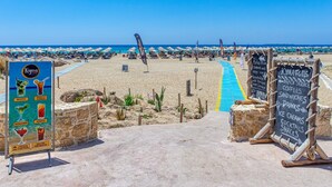 Une plage avec un panneau indiquant les boissons disponibles et un tableau noir affichant les services proposés.