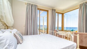 Une chambre d’hôtel avec un lit, une chaise, une table et une vue sur la mer.