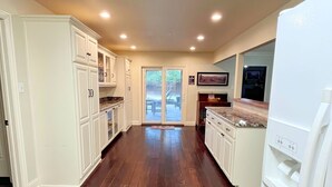 A spacious kitchen with white cabinets, a large refrigerator, and a wooden floor. - Fortunata Casa Del Sole Private House and Poolside Escape (Aubrey)