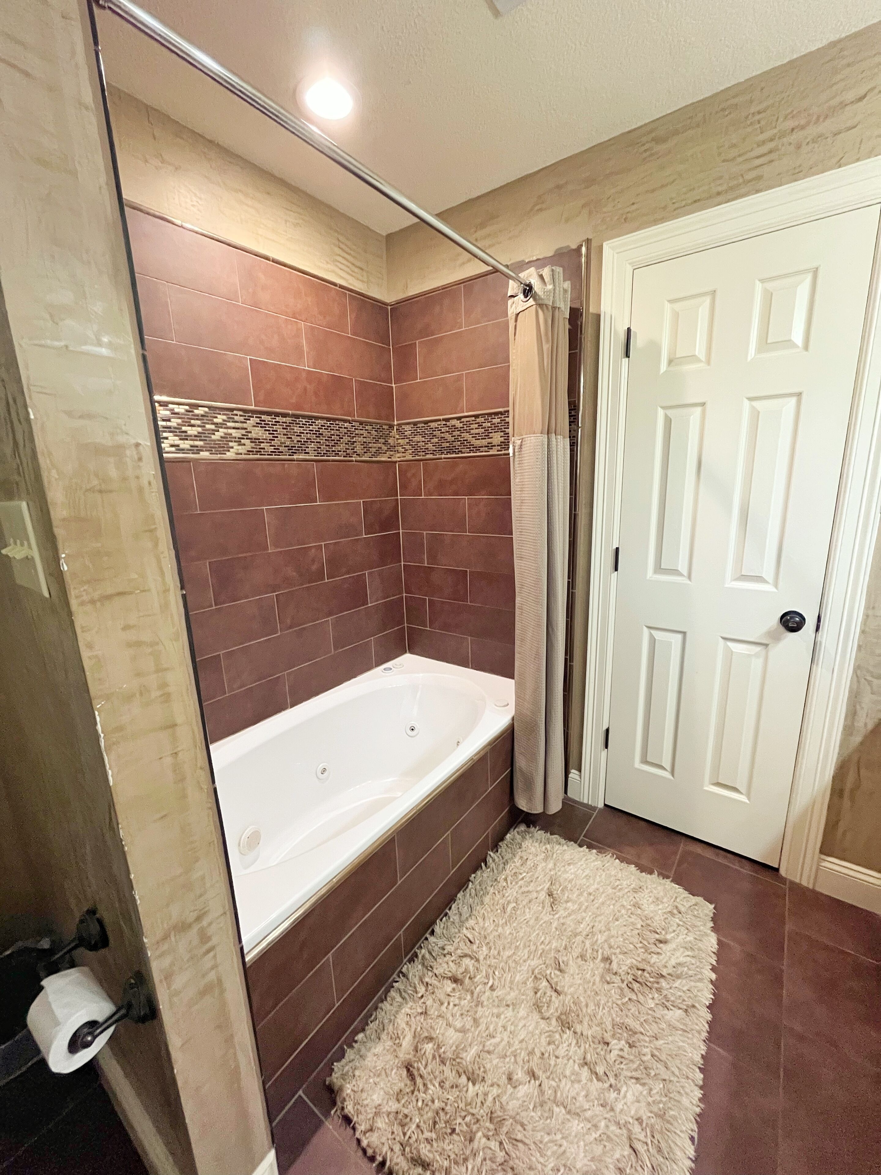 Une salle de bain avec une baignoire, une douche et une porte.