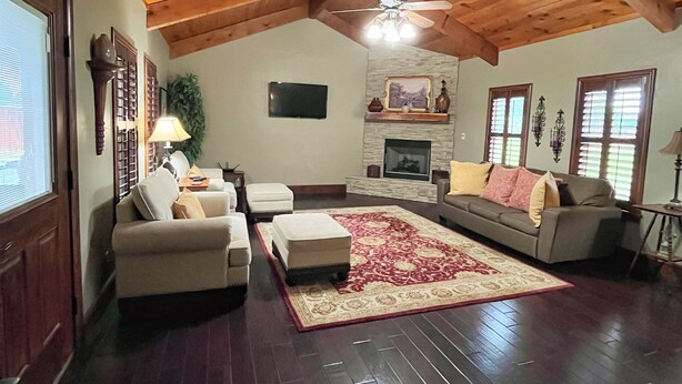 A spacious living room with a high ceiling, wooden beams, a fireplace, a television, and a large window. - Fortunata Casa Del Sole Private House and Poolside Escape (Aubrey)