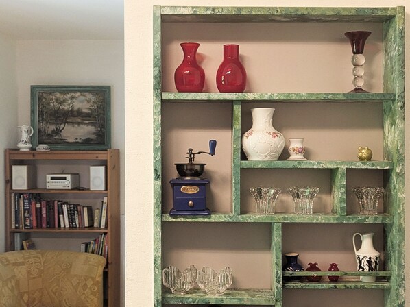 A room with a bookshelf, a vintage coffee grinder, and various glassware on shelves.