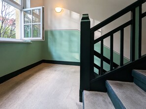 A staircase with a black handrail and a light fixture on the wall.