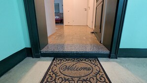 Corredor que leva a um quarto com piso de madeira e tapete de boas-vindas.