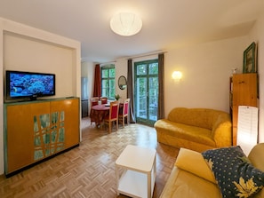 A living room with a sofa, a television, and a dining area with a table and chairs.