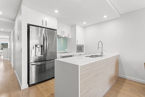 Eine moderne Küche mit einem Edelstahl-Kühlschrank, einer Mikrowelle und einem Spülbecken.