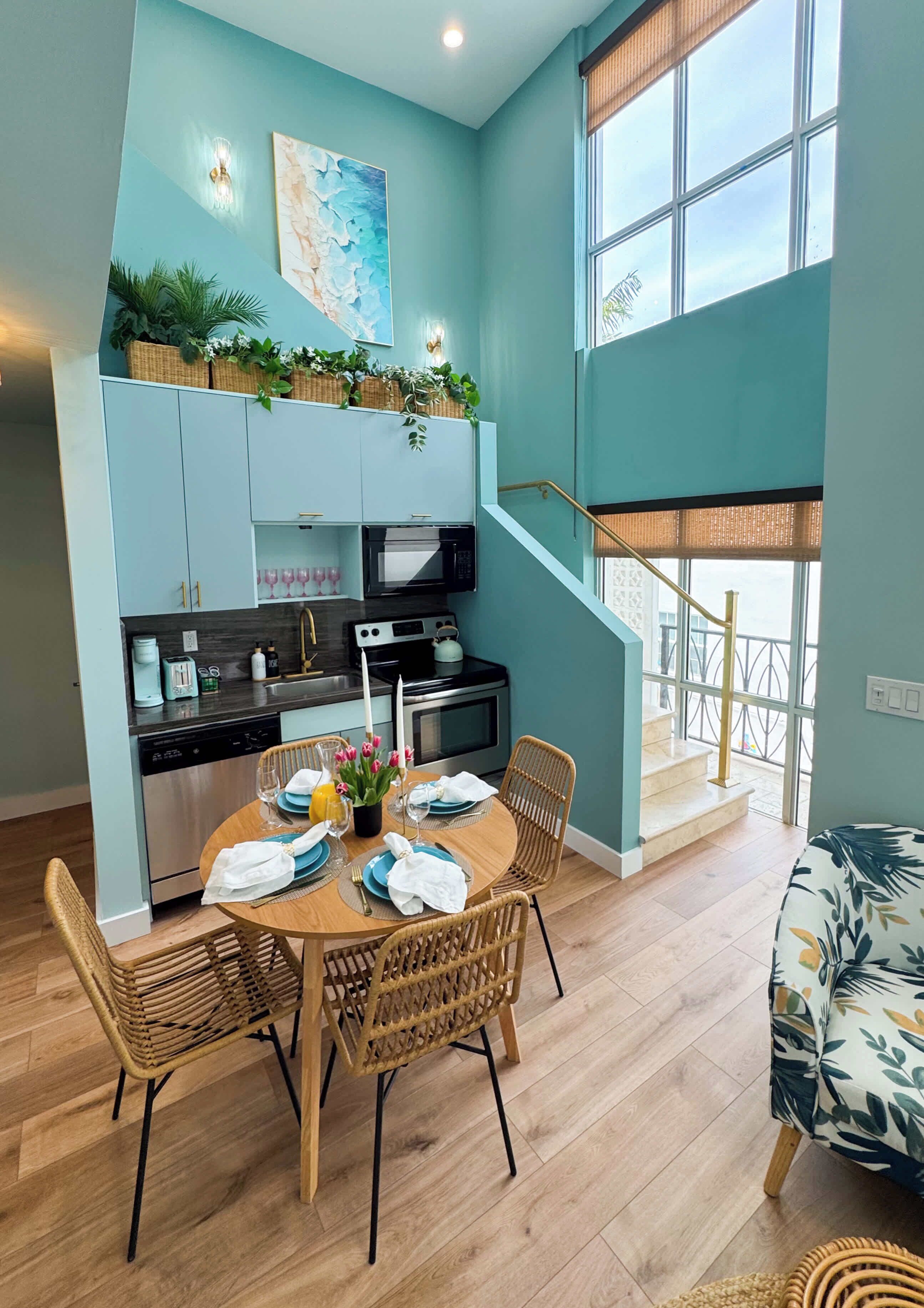 Une cuisine moderne avec un coin repas, un escalier et une vue sur l’extérieur.