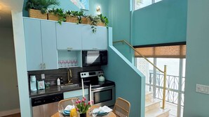 Une cuisine moderne avec un coin repas, un escalier et une vue sur l’extérieur.