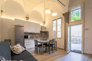 A modern kitchen with white cabinets, a dining table with chairs, and a large window. - Le Volte by Mmega (Florence)