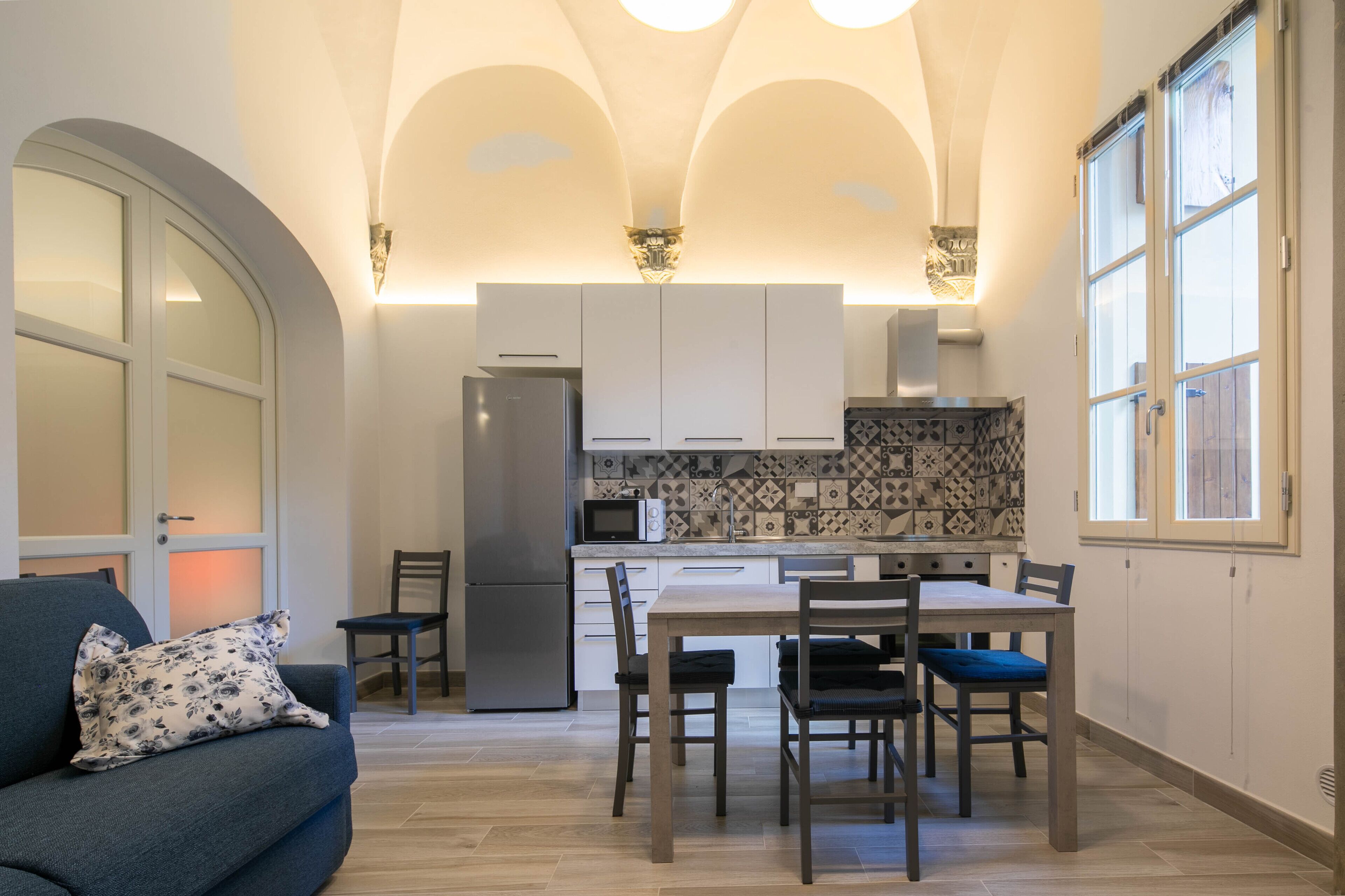 A compact kitchen with a dining area, a refrigerator, and a microwave.