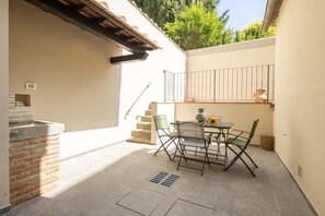 A patio with a table and chairs, a brick wall, and a metal railing. - Le Volte by Mmega (Florence)