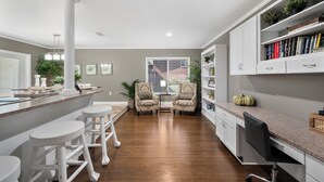 A modern kitchen with a bar area, white cabinetry, and a dining table with chairs.