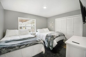 A bedroom with two beds, a white wardrobe, and a desk. - Lakeland Highlands Oasis - 3BR Heated Pool Home (Lakeland)