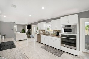 A modern kitchen with white cabinetry, stainless steel appliances, and a central island. - Lakeland Highlands Oasis - 3BR Heated Pool Home (Lakeland)