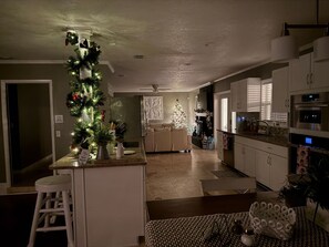 A modern kitchen with white cabinets, a central island, and a dining area with a patterned tablecloth. - Lakeland Highlands Oasis - 3BR Heated Pool Home (Lakeland)