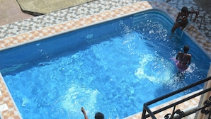Una piscina rettangolare con bordi piastrellati, una scala e una ringhiera in metallo.