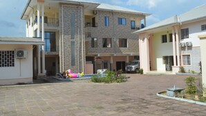 Un edificio residenziale a più piani con un cortile centrale, condizionatori d'aria e un veicolo parcheggiato.
