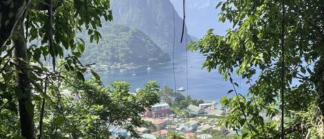 Un pueblo costero con una montaña destacada al fondo, rodeado de abundante vegetación.