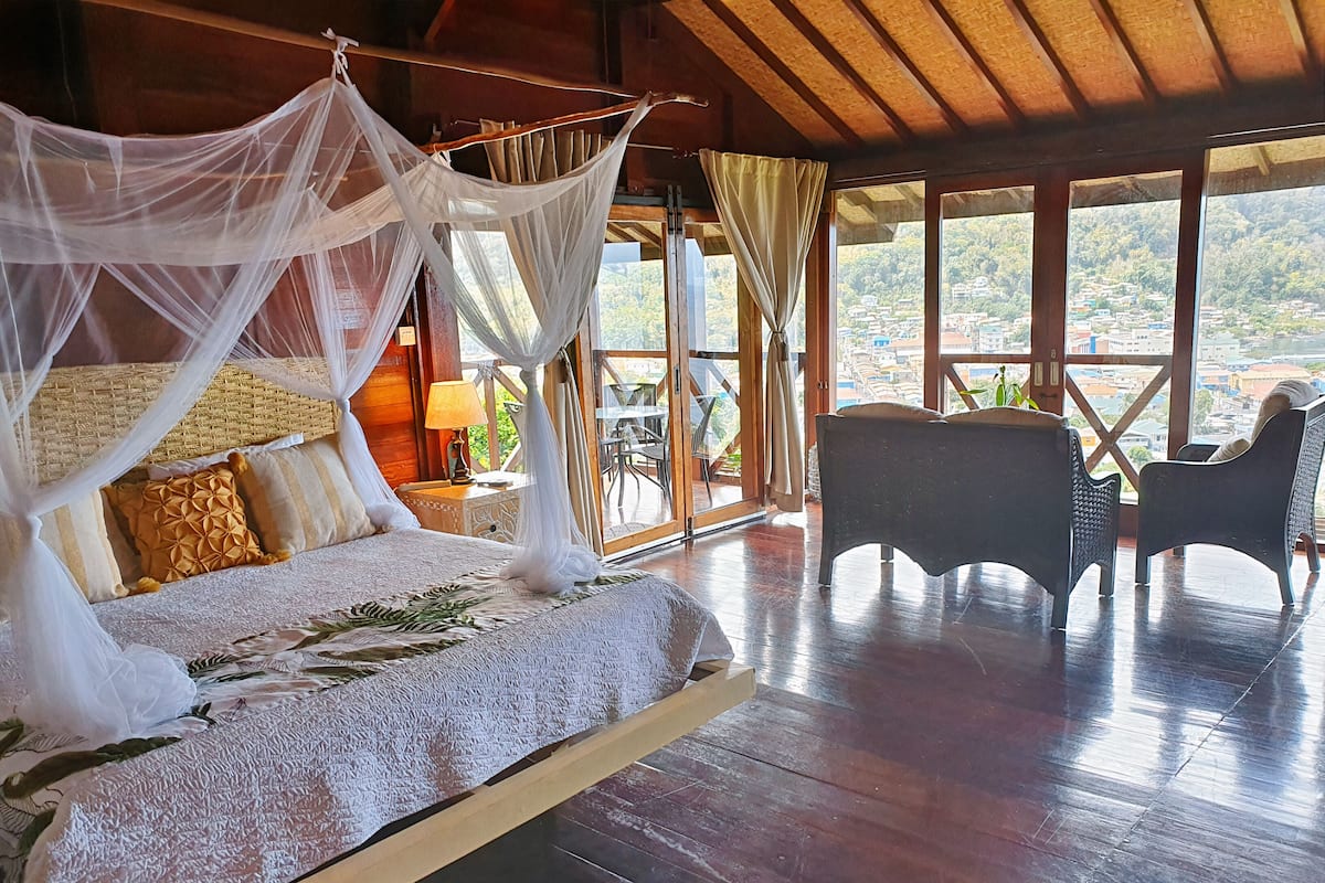 A bed with a canopy, a nightstand, a lamp, and a view of the outside.