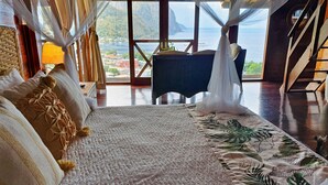 Un dormitorio con una cama grande, vistas al mar y suelo de madera.