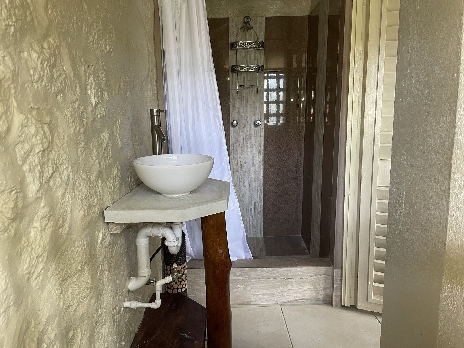 A bathroom with a white sink on a pedestal, a shower area with a glass door, and a white curtain.