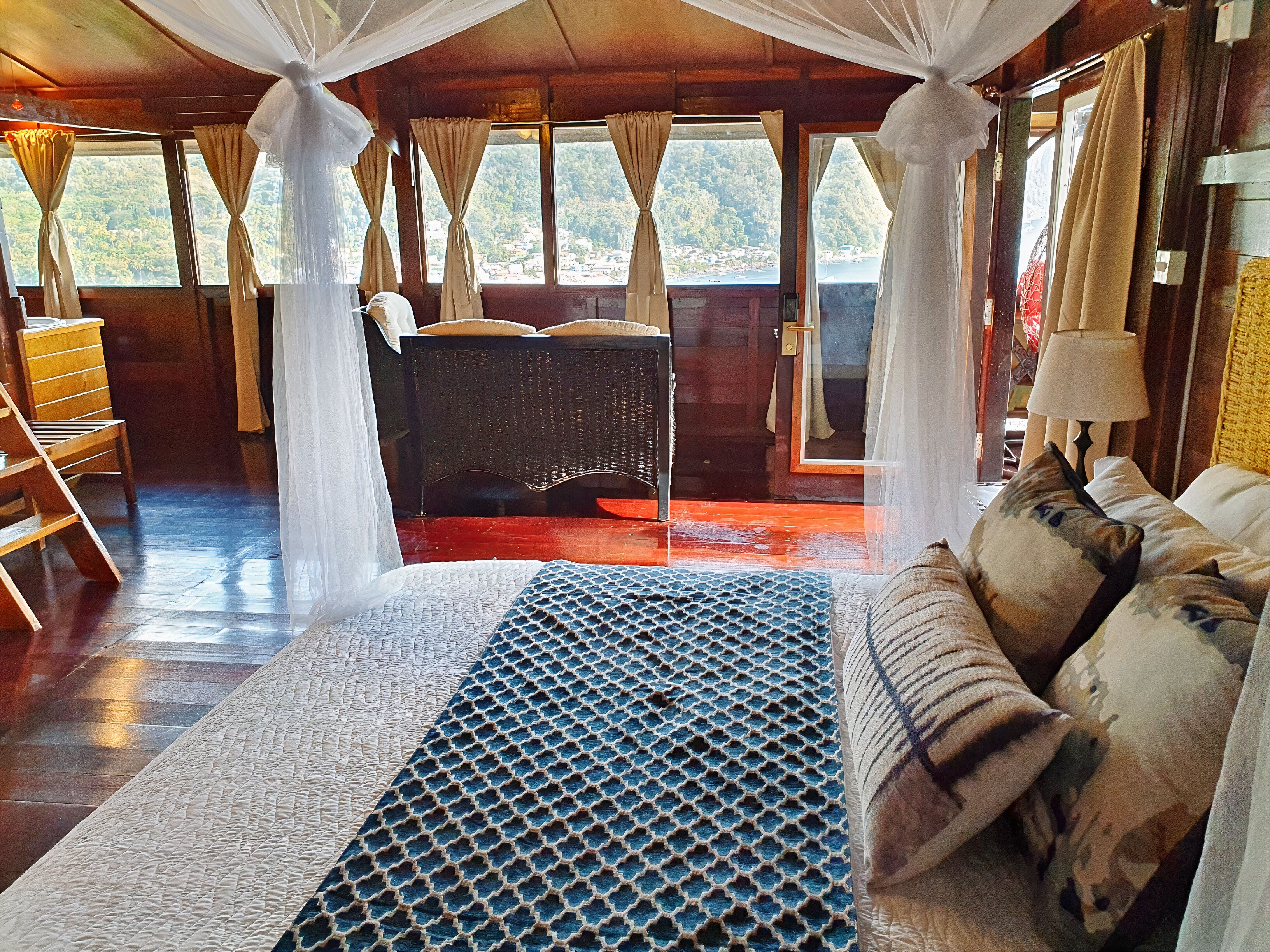 A room with a bed, a chair, and a view of the outdoors.