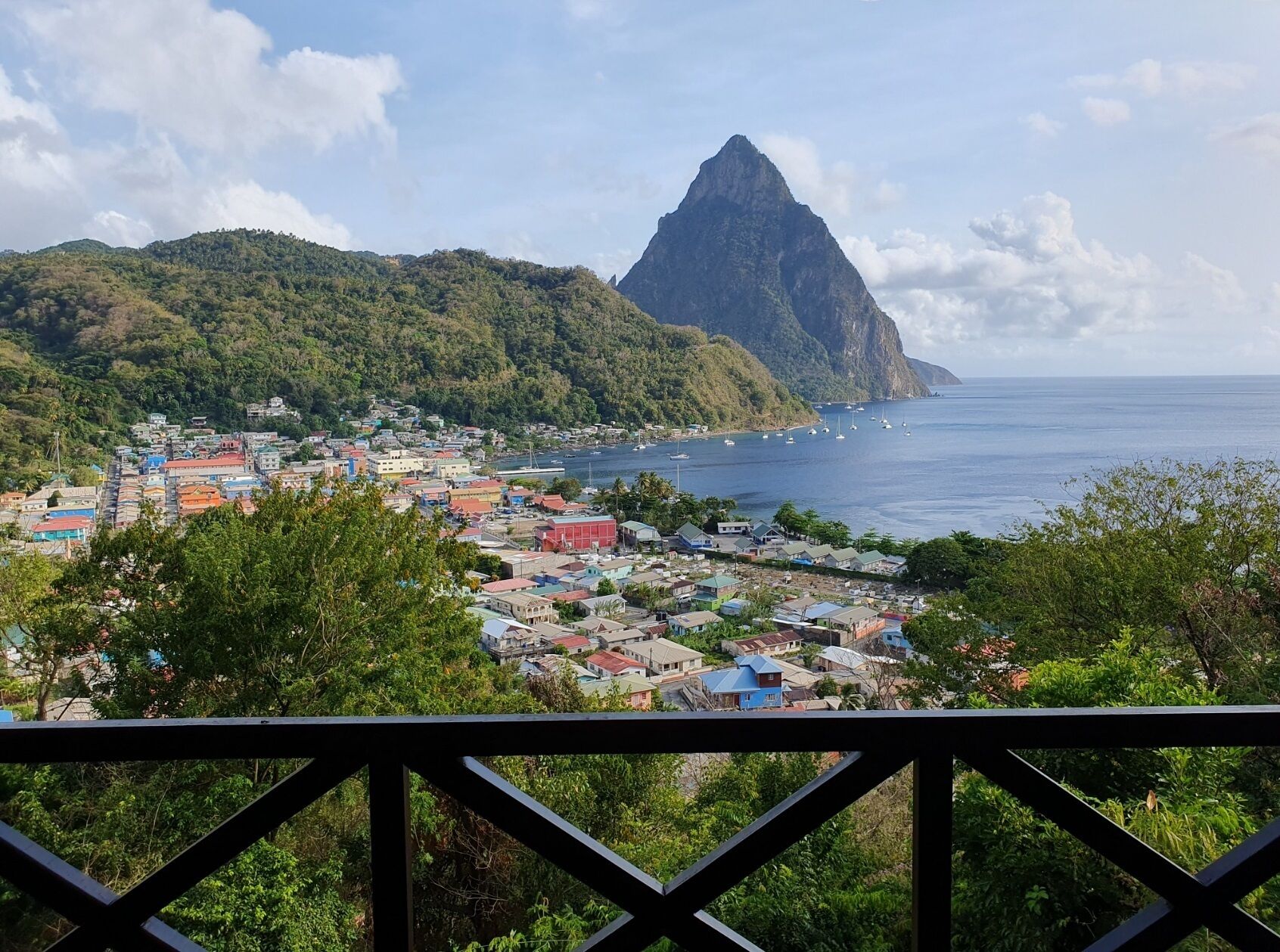 Una località costiera con edifici colorati, una montagna imponente e una vista limpida sul mare.