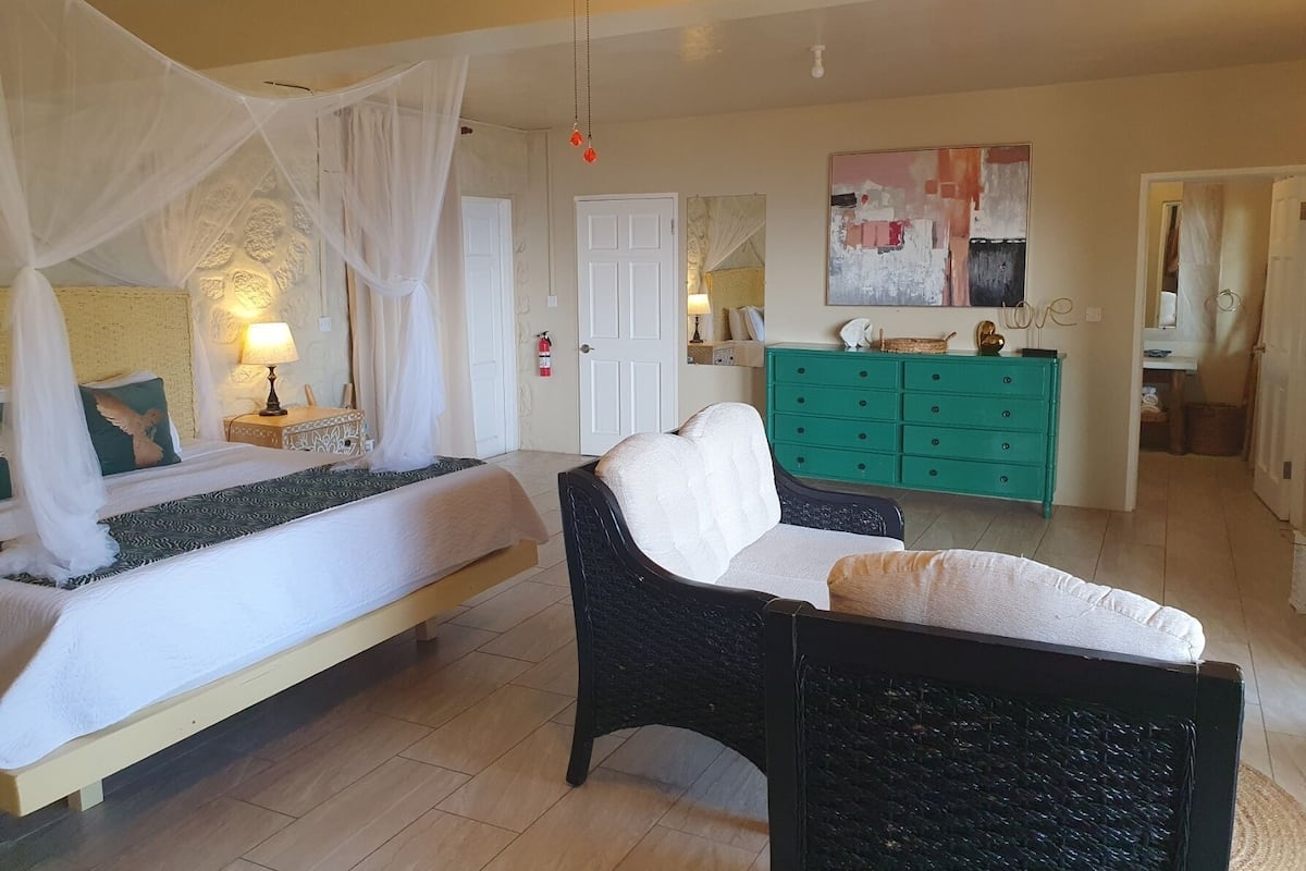 A bedroom with two beds, a green dresser, and a wicker chair.