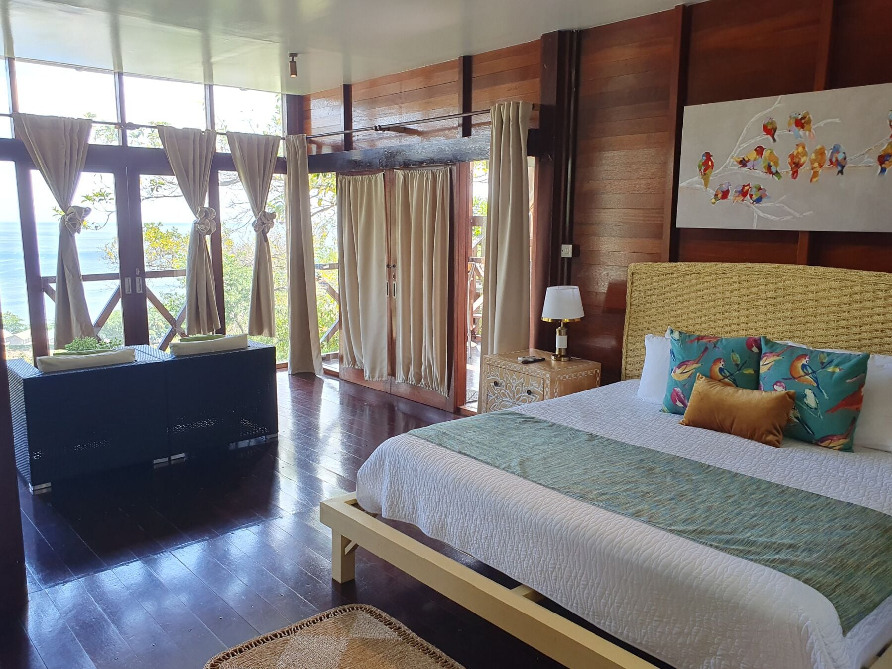 Un dormitorio con cama, televisión, mesita de noche y ventana con cortinas.