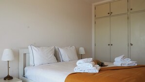 A bedroom with a bed, two bedside lamps, a wardrobe, and folded towels on the bed. - 2 bedroom apartment 30 meters from beach, stunning views Praia da Rocha PORTIMAO (Portimão)