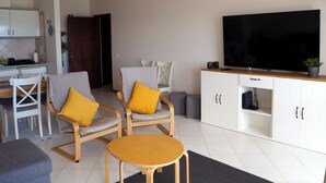A living room with two armchairs, a small round table, a TV, and a white cabinet. - 2 bedroom apartment 30 meters from beach, stunning views Praia da Rocha PORTIMAO (Portimão)