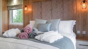 A bedroom with a large bed, wooden paneling on the walls, two pendant lights, and a window with a view of greenery. - 2 bedroom accommodation in Calthwaite, near Penrith (Calthwaite, near Penrith)