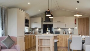 A modern kitchen with wooden cabinets, a central island, and pendant lighting. - 2 bedroom accommodation in Calthwaite, near Penrith (Calthwaite, near Penrith)
