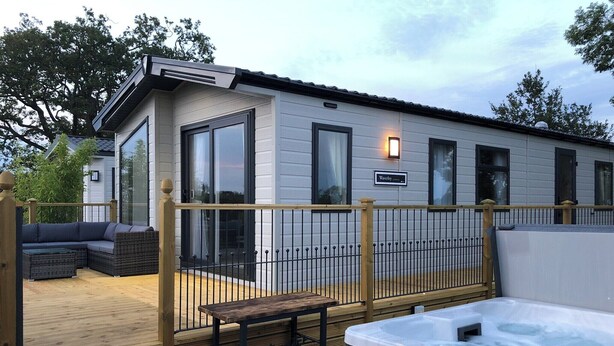 A modern outdoor deck with a hot tub, wooden steps, and a seating area. - 2 bedroom accommodation in Calthwaite, near Penrith (Calthwaite, near Penrith)